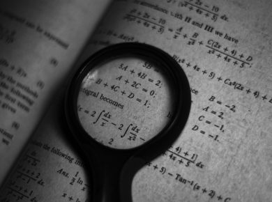 Ein Bild einer Lupe und eines Mathematikbuches.